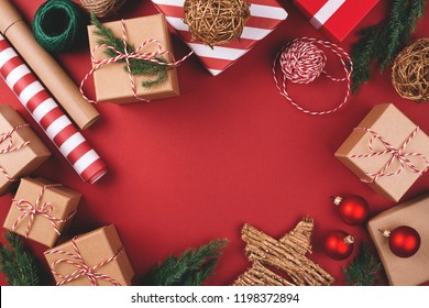 Christmas background with gift boxes, clews of rope, paper's rools and decorations on red. Preparation for holidays. Top view with copy space. - Shutterstock ID 1198372894