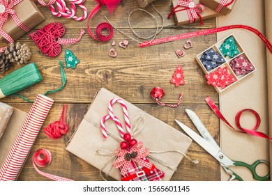 Christmas background with gift boxes, ribbons, paper rolls, decorations and candy canes on wooden table. Preparation for holidays. Top view with copy space.