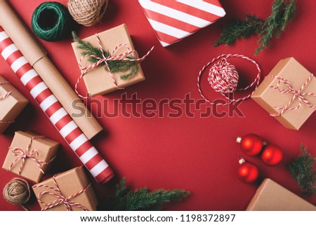 Christmas background with gifts and decorations on red. Preparation for holidays. Top view with copy space.