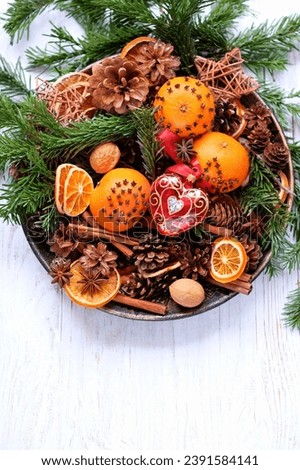 Christmas background. glass Heart toy, cones, fir branches, cinnamon, oranges decorated cloves in plate on wooden table. Christmas, Advent, New Year, Yule holidays. festive winter season. top view