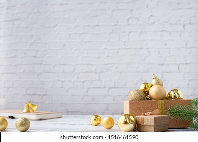 Christmas Background With Gold Bauble Gift Box  On White Brick Wall Texture Background, View From Front Table.