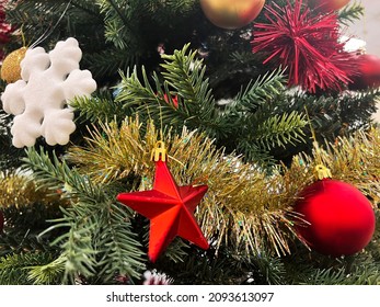 Christmas background, green pine branches festive background. New year decoration with red star and bubble, white snowflake. Botanical selective focus.