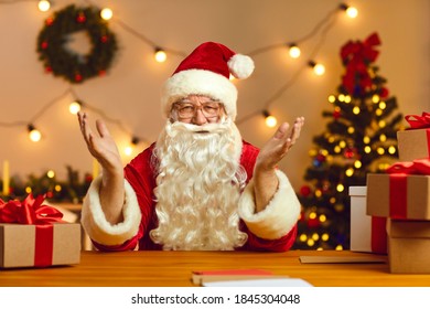 Christmas background. Happy Santa Claus talking on video call with kids using webcam on laptop. Man in a red suit with a white beard sits at home at a table with gifts on Christmas Eve. - Powered by Shutterstock