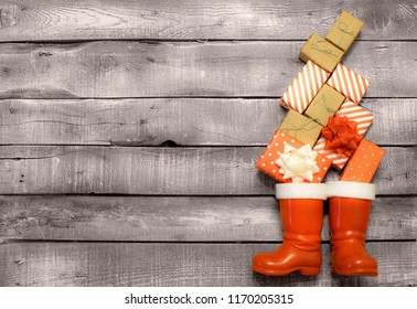 Christmas Background - Red And Brown Gifts Fall Down In Santas Or Saint Nicholas Boots On Grey Rustic Wooden Background 