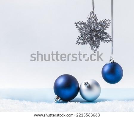 Christmas background, silver ribbon and blue and silver balls, star and artificial snow on a light background. Creative composition with copy space. New year, christmas, holiday, decoration.