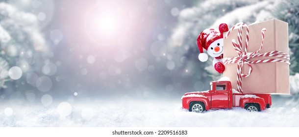 Christmas background with snow, snowman and retro red car with gift box. Merry Christmas and happy New Year greeting winter card with copy-space - Powered by Shutterstock