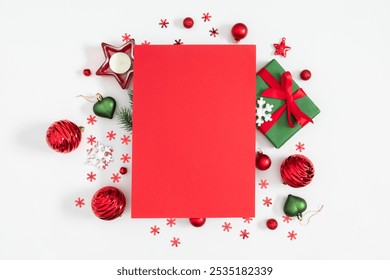 Christmas background. Top view of red empty sheet of paper and Christmas red decorations, balls, candles, gift and confetti on white table background. Flat lay. Christmas card. - Powered by Shutterstock