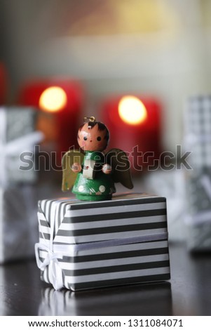 Christmas background with traditional handmade angel, gifts, red candles, bokeh light and festive decoration.