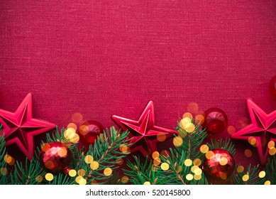 Christmas background with xmas tree, red ornaments and glowing golden bokeh lights on red canvas background. Merry christmas card. Winter holiday theme. Space for text. Happy New Year.
