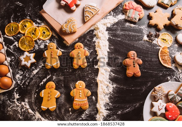 Christmas
bakery. Creative pastry collection. Ethnic diversity. Black lives
matter. Chocolate icing gingerbread man dividing from white
biscuits flour line on festive decorated
desk.