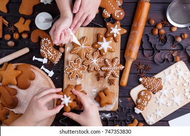 Christmas bakery. Friends decorating freshly baked gingerbread cookies with icing and confectionery mastic, view from above. Festive food, family culinary, Christmas and New Year traditions concept