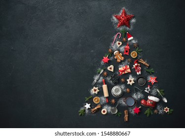 Christmas baking background with fir tree made from kitchen utensils, cookies, spices, cinnamon sticks, anise stars, top view