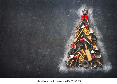 Christmas baking background with fir tree made from kitchen utensils, cookies, spices, cinnamon sticks, anise stars on rustic baking tray, top view - Powered by Shutterstock