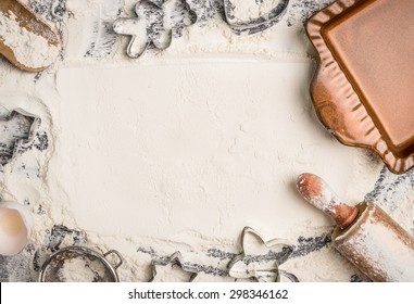 Christmas baking background with flour, rolling pin, cookie cutter and  rustic bake pan, top view, place for text. Horizontal