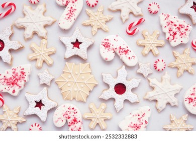 Christmas baking background with a selection of red and white theme cookies and candies. Overhead view on a white marble background. Holiday candy cane baking concept.