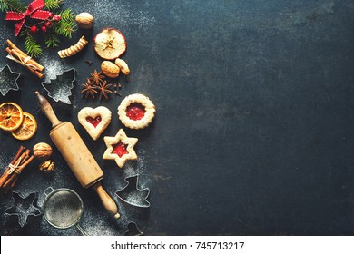 Christmas Baking Sweet Food Background With Homemade Cookies, Spices, Kitchen Utensils, Fir Branches And Red Holiday Decoration On Dark Rustic Baking Tray. Top View