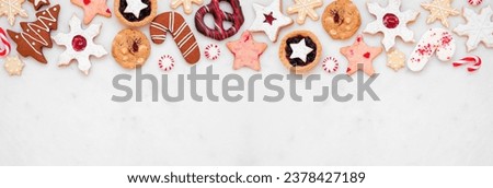 Christmas baking top border with a variety of cookies and sweet treats. Above view on a white marble banner background with copy space. Holiday baking concept.