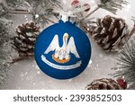 Christmas ball with the flag of Louisiana, decorates the snow tree with snowfall. The concept of the Christmas and New Year holiday