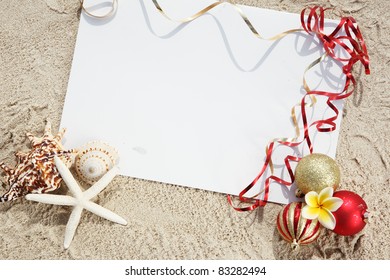 Christmas Balls And Seashells With Blank Card On The Beach.