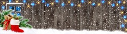 Christmas Banner. Santa Boot And Bag With Gifts And Cones On Wooden Wall Background And Glowing Lights Outside The Window.
