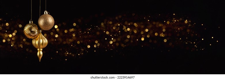 Christmas banner with three golden decoration balls on black background with bokeh lights with copy space. Wide panoramic header - Powered by Shutterstock