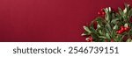 Christmas banner with vibrant green leaves and red berries on a rich red backdrop. Xmas and winter holidays celebration concept