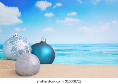 Christmas baubles in the sand on a beach on a bright and sunny day. - Powered by Shutterstock