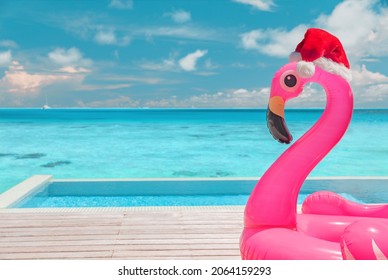 Christmas Beach Summer Vacation Flamingo Pool Float With Santa Hat Travel Background For Winter Holidays.