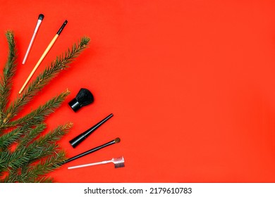 Christmas Beauty Cosmetics Composition With Brushes Tools And Accessories With New Year Fir Spruce Branches Decorations On Red Background. Stylish Concept. Flat Lay, Mock Up Top View With Copy Space.