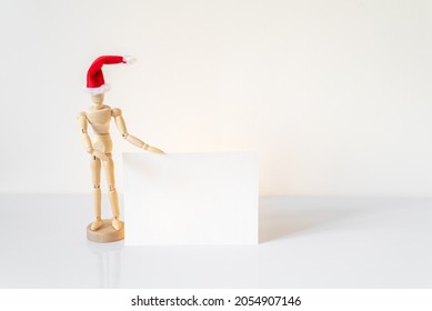 Christmas blank greeting card mock-up scene. Wooden mannequin posing on greeting card or gift list with red Santa Claus hat.Modern and minimal Santa Claus. - Powered by Shutterstock