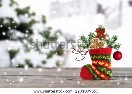 Christmas boot of Santa Claus with pine branches, gingerbread and toys on a winter background. Winter holiday.