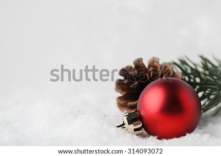 A Christmas border and background with red bauble, fir cone and green branch, nestling in white fake snow in lower right corner.  Twinkling stars in background above.