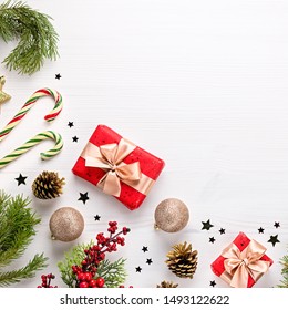 Christmas border flat lay with pine, presents, golden elements, candy canes, confetti. Christmas template on light wood - Shutterstock ID 1493122622