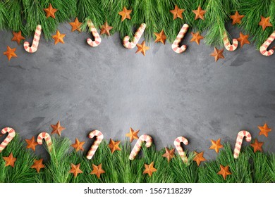 Christmas Border Of Pine Boughs, Rustic Stars And Wooden Candy Canes On Slate Surface, Copy Space In The Middle.