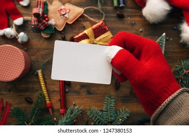 Christmas Business Card Mock Up Held By The Hand Over Table With Various Holiday Decorations