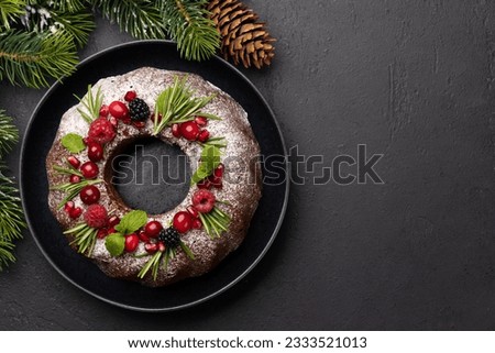 Christmas cake decorated with pomegranate seeds, cranberries and rosemary. Flat lay with copy space