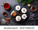 Christmas cakes, puddings on marble cutting board with cup of tea. Grey background. Top view.