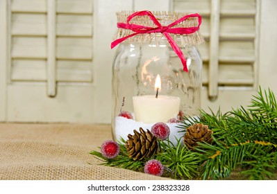 Christmas Candle In A Mason Jar With Pine Bough And Sparkling Red Berry