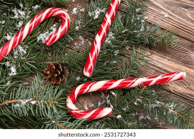 Christmas candy canes with fir branches and pine cone on wooden background - Powered by Shutterstock