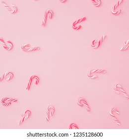 Christmas candy canes on pink background, fame with copy space. Flat lay winter concept.