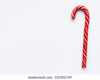 Christmas candy cone on white background. Colorful holiday sweet lollipop with copy space. Dessert wtih red and white stripes.