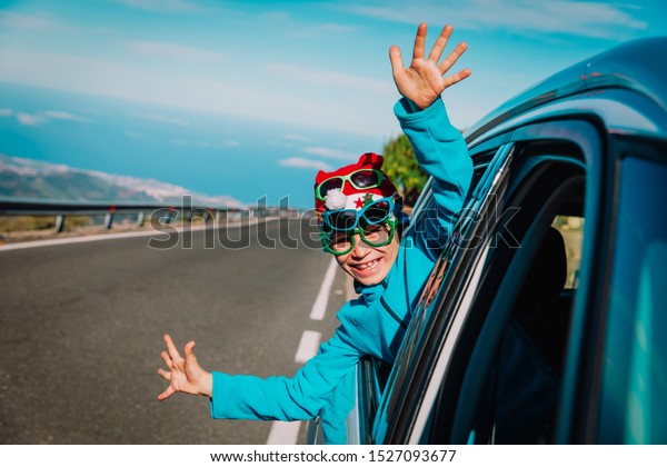 christmas car travel- happy child travel on road\
in winter