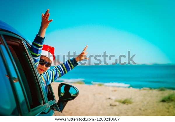 christmas car travel- happy little boy travel in\
winter on beach