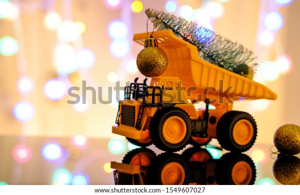 Christmas card. Children\'s truck carries a\
Christmas tree. Merry christmas concept. Light blurred background.\
Bokeh, multicolor\
color.