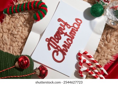 A Christmas card with cute decorative objects such as candy canes, wool scarves, Noel balls, and snow globes displayed in a fur rug on a red background, an idea for a Christmas photo template. - Powered by Shutterstock