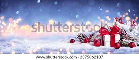 Christmas Card - Gift On Snow - Blue Snowing With Bokeh Lights And Ornament In Fir Branch - Abstract Defocused Background