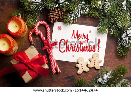 Christmas card with gingerbread cookies and fir tree branch covered by snow on stone background. Top view