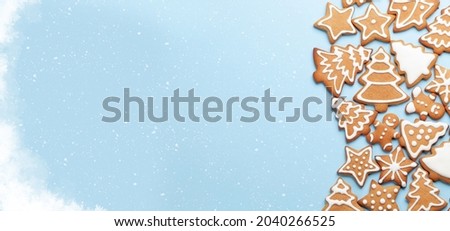 Christmas card with gingerbread cookies over blue background. Top view flat lay with space for xmas greetings