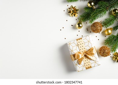 Christmas Card Mockup. Fir Tree Branch With Golden Balls, Gift Box And Confetti On White Background With Copy Space. Xmas Banner, New Year Postcard Template. Flat Lay, Top View.