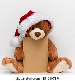 Christmas Card With Teddy Bear  With A Gift And Holiday Decoration. Christmas Teddy Bear Holding A Place For Text And Other Christmas Decor. 